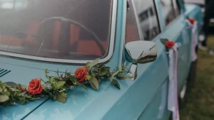 Voiture bleue décorée de roses rouges et de feuillage