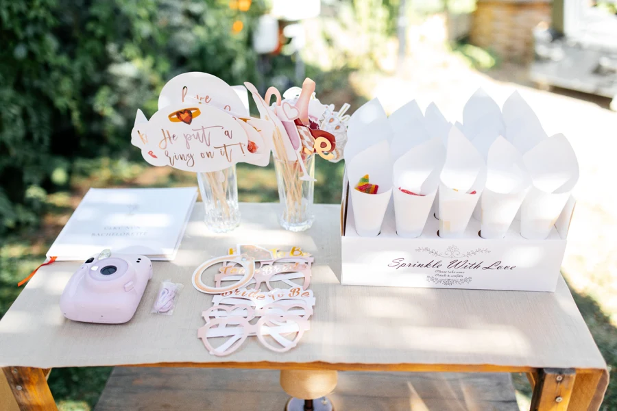 Table de photobooth dans un jardin : appareil instantané, lunettes et accessoires