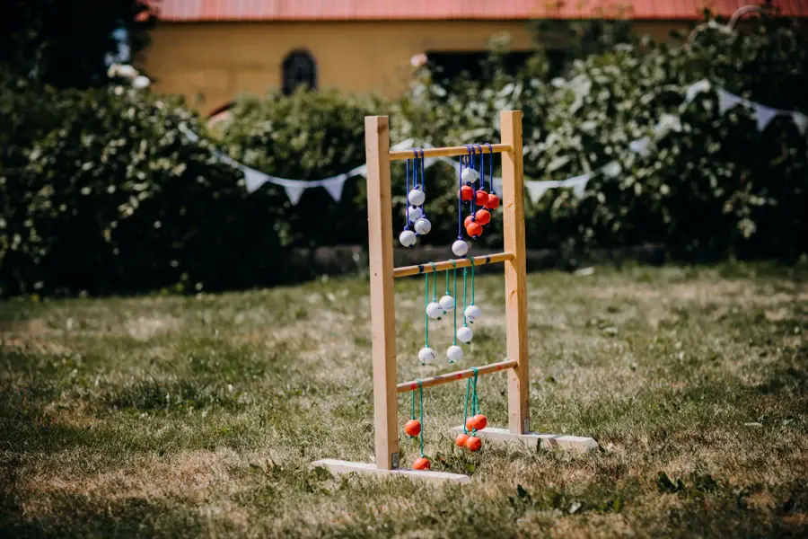 Jeu d'anneaux en bois installé sur une pelouse, devant une haie fleurie